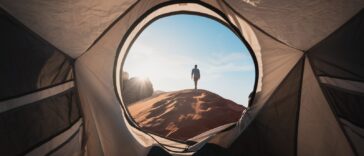 a man standing in a tent looking out into the distance